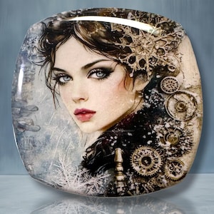 May include: A square decorative plate featuring a detailed illustration of a person with dark hair, blue eyes, and pink lips. The design incorporates metallic-toned mechanical gears and white snowflake patterns against a textured gray background.