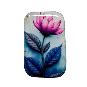 May include: A rectangular, glass-like object featuring a watercolor painting of a pink flower with blue leaves and stem. The background is a blend of blue and white hues, creating a soft, artistic aesthetic. The flower is the focal point.