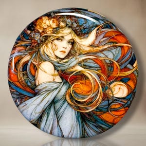 May include: A circular decorative piece featuring an illustration of a person with long flowing blonde hair adorned with orange and blue flowers. The person wears a light blue garment, and the background consists of swirling orange and blue lines.