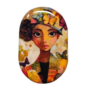 May include: Oval-shaped art piece featuring a stylized portrait of a woman with dark skin, large eyes, and a hat adorned with butterflies. The artwork uses a warm color palette with yellows, oranges, and reds, creating a whimsical and artistic aesthetic.