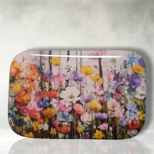 May include: A rectangular glass tray featuring a vibrant, multi-colored floral print. The design displays a dense meadow of wildflowers in shades of yellow, orange, pink, purple, and blue, set against a soft, light-colored background.