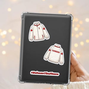 May include: Two white fleece jacket stickers with red accents and maple leaf details are displayed on a black tablet. One sticker has the word "CANADA" in red. The phrase "#ReleaseTheFleece" is also visible.