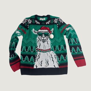 May include: A green long-sleeve sweater featuring a white llama wearing a red Santa hat and green sunglasses. The sweater has a dark blue collar, cuffs, and hem, with a repeating pattern of white snowflakes and dark blue pine trees across the chest.