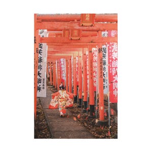 Könnte beinhalten: Ein junges Mädchen in einem rot-weißen Kimono geht durch ein traditionelles japanisches rotes Torii-Tor. Das Tor ist mit japanischen Schriftzeichen verziert und das Mädchen ist von roten Laternen umgeben.