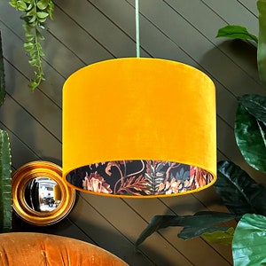 Può includere: Un paralume in velluto giallo con una fodera a stampa floreale. Il paralume è appeso a un apparecchio di illuminazione a soffitto.
