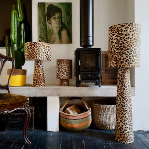 May include: Three leopard print lamps of varying sizes and shapes, a wood-burning stove, and woven baskets on a shelf.