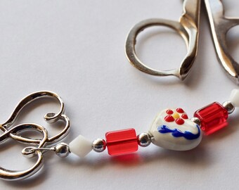 Small folding scissors with decorative beaded fob, white, red and blue heart beads and a silver two hearts charm.