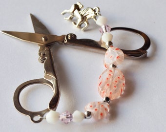 Small folding scissors with decorative red and white beaded fob and a silver unicorn charm.