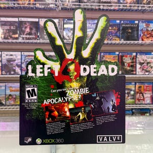 May include: A promotional cardboard display for the Left 4 Dead video game on Xbox 360. The sign features a green zombie hand graphic, the title text, the ESRB Mature 17+ rating, and the question Can you survive the ZOMBIE APOCALYPSE? with game imagery.