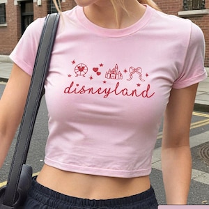 May include: Pink cropped t-shirt with a red graphic of a castle, a Ferris wheel, hearts, and a bow with the text "disneyland" in red.