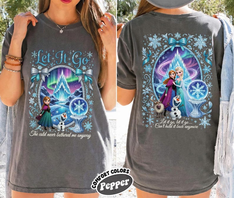 Puede incluir: Camiseta gris carb&oacute;n con un gr&aacute;fico colorido de la pel&iacute;cula Frozen. El dise&ntilde;o frontal incluye el texto "Let It Go" y la frase "The cold never bothered me anyway." El dise&ntilde;o trasero muestra a Elsa y Anna con el texto "Let it go, let it go... Can't hold it back anymore."