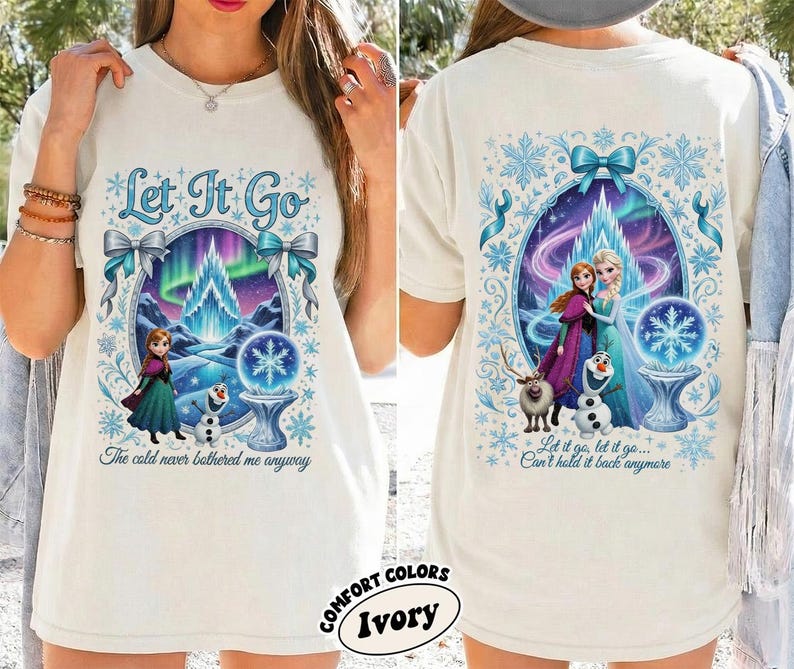 Puede incluir: Camiseta color marfil con un dise&ntilde;o colorido de la pel&iacute;cula Frozen. El frente presenta el texto "Let It Go" y una escena con Anna, Elsa y Olaf. La parte posterior de la camiseta muestra los mismos personajes y el texto "Let it go, let it go... Can't hold it back anymore."