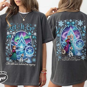 Puede incluir: Camiseta gris oscuro con un gr&aacute;fico colorido de Frozen. El dise&ntilde;o frontal incluye el texto "Let It Go" y una escena con Anna, Elsa y Olaf. La parte trasera de la camiseta tiene un dise&ntilde;o similar con el texto "Let it go, let it go... Can't hold it back anymore".