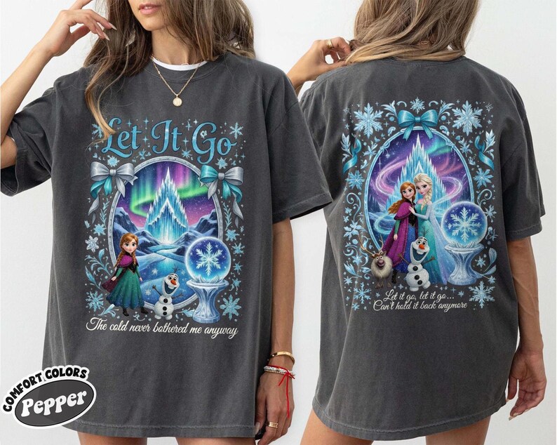 Puede incluir: Camiseta gris oscuro con un gr&aacute;fico colorido de Frozen. El dise&ntilde;o frontal incluye el texto "Let It Go" y una escena con Anna, Elsa y Olaf. La parte trasera de la camiseta tiene un dise&ntilde;o similar con el texto "Let it go, let it go... Can't hold it back anymore".