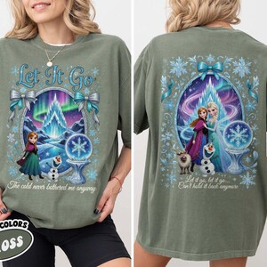 Puede incluir: Camiseta verde musgo con un gr&aacute;fico de la pel&iacute;cula Frozen. El dise&ntilde;o frontal incluye el texto "Let It Go" y una escena invernal con Anna, Elsa y Olaf. El dise&ntilde;o trasero muestra los mismos personajes y el texto "Let it go, let it go... Can't hold it back anymore."