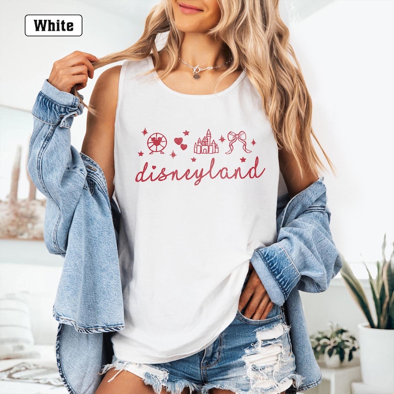 May include: White tank top with a red graphic of a castle, a Ferris wheel, hearts, and a bow. The text "disneyland" is written in red below the graphic.