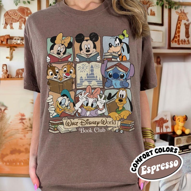 Puede incluir: Camiseta color espresso con un gr&aacute;fico de personajes de Disney leyendo libros. El dise&ntilde;o incluye a Minnie Mouse, Mickey Mouse, Goofy, Chip y Chop, Stitch, Donald Duck, Daisy Duck y Pluto. Tambi&eacute;n est&aacute; presente el texto "Walt Disney World Book Club".