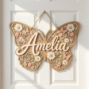 May include: A butterfly-shaped wooden wall sign featuring the name Amelia in white script lettering. The sign is decorated with raised white daisies, pink roses, green leaves, and small pink butterflies attached to the natural wood surface.