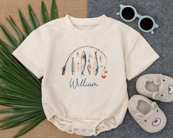 May include: A cream-colored baby onesie with a fishing rod and fish design. The onesie has the name "William" printed on the front.