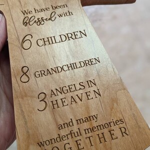 Pu&ograve; includere: Una croce di legno con il testo "We have been blessed with 6 CHILDREN 8 GRANDCHILDREN 3 ANGELS IN HEAVEN and many wonderful memories TOGETHER" inciso su di essa.