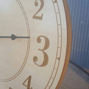May include: A wooden clock face with Roman numeral markings. The clock face is light brown with a darker brown border. The numbers 1, 2, 3, 4, and 5 are visible.