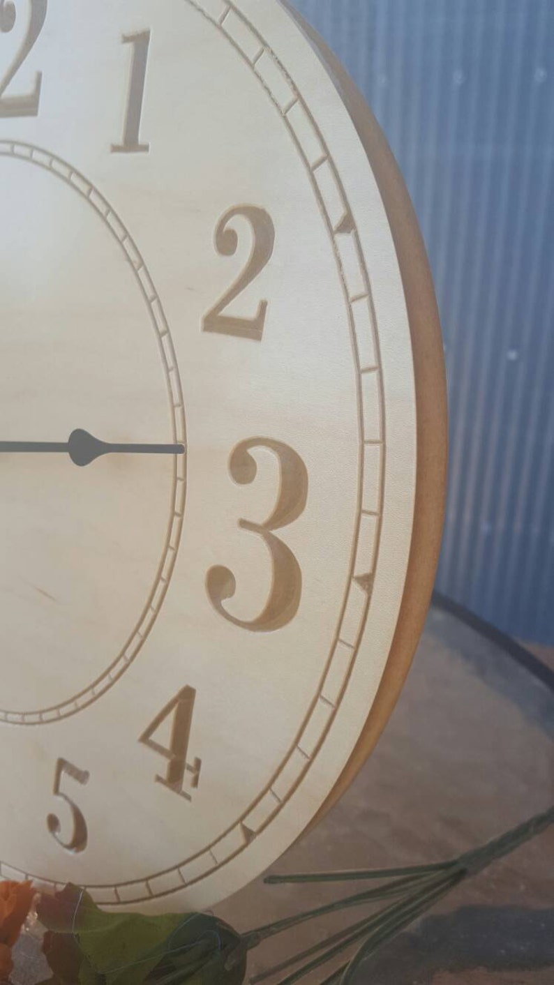 May include: A wooden clock face with Roman numeral markings. The clock face is light brown with a darker brown border. The numbers 1, 2, 3, 4, and 5 are visible.