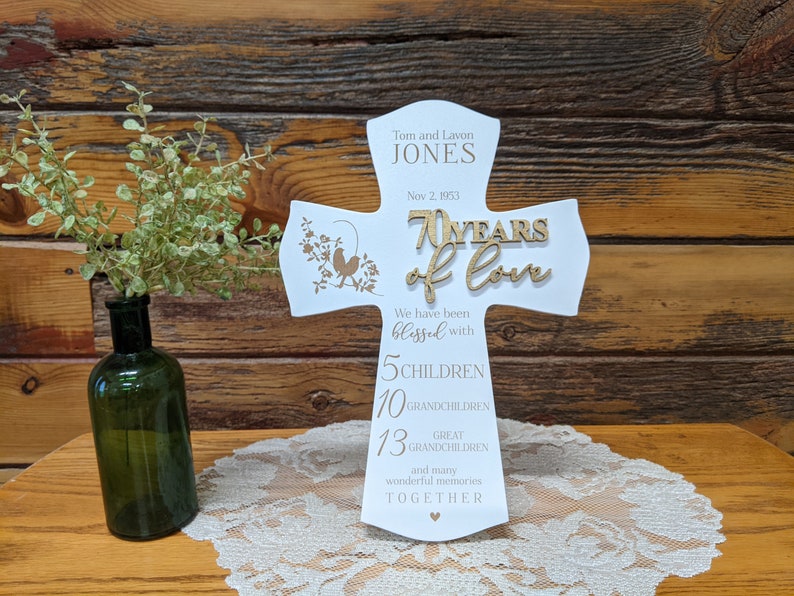 Pu&ograve; includere: Una croce di legno bianco con un'iscrizione dorata che celebra 70 anni d'amore. L'iscrizione include i nomi Tom e Lavon Jones, la data 2 novembre 1953 e il numero di figli, nipoti e pronipoti. La croce &egrave; decorata con un piccolo disegno di uccelli.
