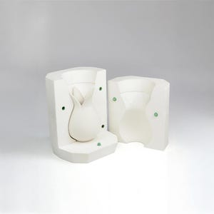 May include: Two-piece white ceramic mold for making a vase shaped like a flower bud.