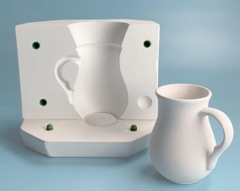 May include: White ceramic mold for making a pitcher, with a white ceramic pitcher next to it.