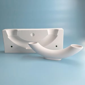 Puede incluir: Molde de cerámica blanca para hacer un jarrón curvo. El molde está en dos piezas, una para la base y otra para la parte superior curva. El molde se muestra sobre un fondo azul claro.