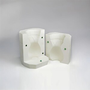 May include: Two white ceramic molds for making a vase or pitcher. The molds are open and show the inside of the vase shape. The molds have small green circles on the sides.