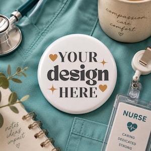 May include: A round white button featuring the dark grey text YOUR design HERE, decorated with two small hearts and two four-pointed stars. The button sits on a teal fabric surface next to a stethoscope, a mug, a notebook, and a nurse ID badge.