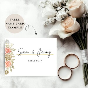 May include: A white table name card with floral accents and the names "Sam & Jenny" in elegant script. The card also includes "Table No. 9". A bouquet of white and peach roses and two gold wedding rings are also in the image.