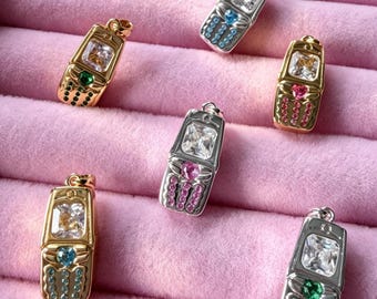 May include: Six metallic pendants shaped like vintage flip phones, each featuring a large rectangular clear stone at the top, a small heart-shaped stone in the center, and rows of tiny colored accent stones representing a keypad.
