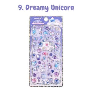 Może przedstawiać: Arkusz wypukłych naklejek z napisem 9. Dreamy Unicorn, przedstawiający r&oacute;żne małe, p&oacute;łprzezroczyste i brokatowe ikony, w tym jednorożce, gwiazdki, chmury i słodycze w odcieniach fioletu, błękitu i r&oacute;żu na holograficznej karcie podkładowej.