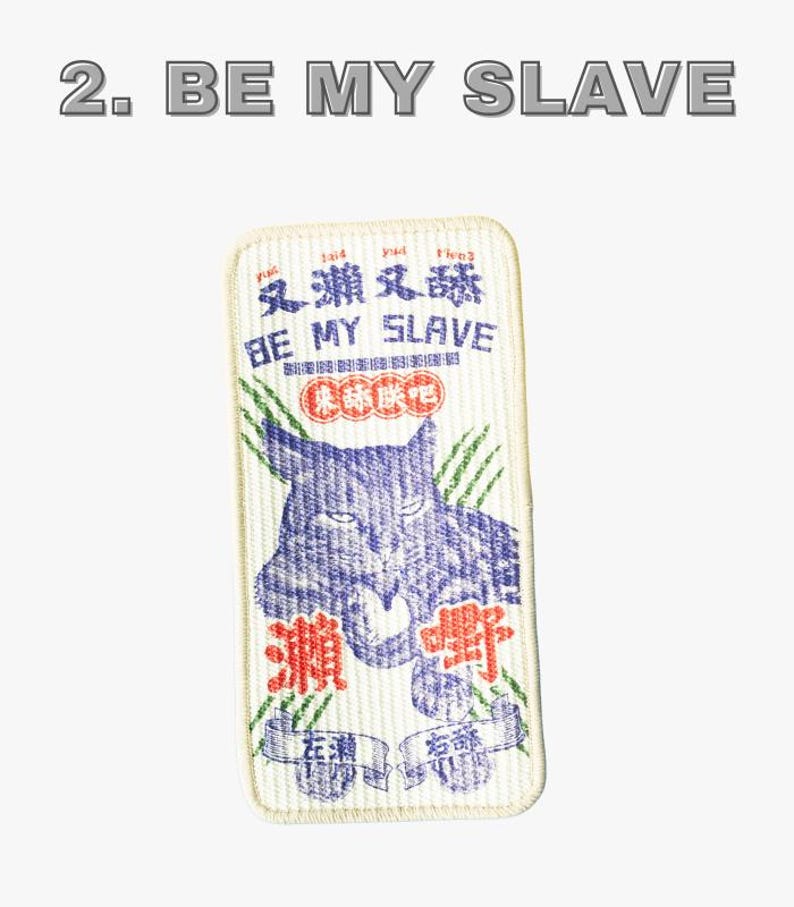 Może przedstawiać: Prostokątna naszywka z napisem "2. BE MY SLAVE" u g&oacute;ry. Naszywka przedstawia niebieską ilustrację kota i chińskie znaki. Fraza "BE MY SLAVE" jest r&oacute;wnież napisana na naszywce.