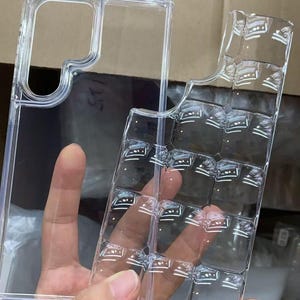 Puede incluir: Funda transparente para tel&eacute;fono con un dise&ntilde;o &uacute;nico. La funda est&aacute; hecha de pl&aacute;stico transparente y tiene forma rectangular con recortes para la c&aacute;mara y los botones del tel&eacute;fono. La funda est&aacute; dise&ntilde;ada para proteger el tel&eacute;fono de ara&ntilde;azos y da&ntilde;os.