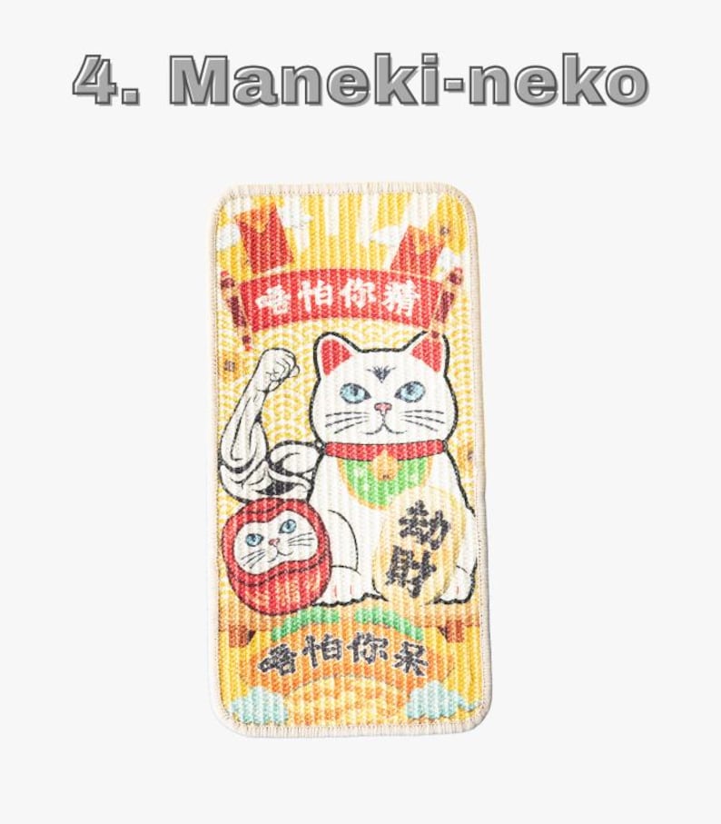 Może przedstawiać: Prostokątna naszywka z białym kotem Maneki-neko z niebieskimi oczami, czerwoną obrożą i zielonym śliniakiem. Kot jest przedstawiony z uniesioną ręką i znajduje się obok czerwonej lalki Daruma. Tło jest ż&oacute;łte z chińskim tekstem i słowami "Maneki-neko" u g&oacute;ry.