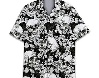 Peut inclure: Une chemise à manches courtes boutonnée sur le devant, présentant un fond noir avec un motif graphique répétitif blanc composé de crânes humains et de roses en fleurs. Elle possède un col classique et une étiquette ACE au niveau du col.