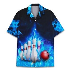 Puede incluir: Una camisa de botones de manga corta azul y negra con una bola de bolos y bolos en llamas.