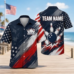 May include: A short-sleeve button-down shirt featuring a patriotic design with navy blue, white, and red colors. The front displays a bowling ball and pins graphic with the text YOUR NAME, while the back features the text TEAM NAME.