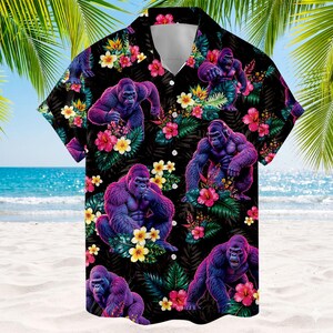 May include: A short-sleeved button-down shirt featuring a black background with a repeating pattern of purple gorillas, vibrant pink hibiscus flowers, and yellow plumeria blossoms. The shirt has a classic collar and a front button closure.