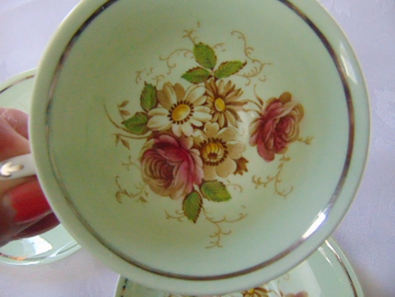 Paragon footed cup and 2 saucers in green floral small brown mark on the cup