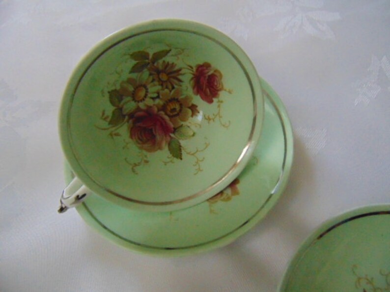 Paragon footed cup and 2 saucers in green floral small brown mark on the cup