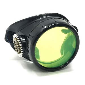 May include: Black steampunk goggles with a bright yellow lens and a brass gear detail on the side.
