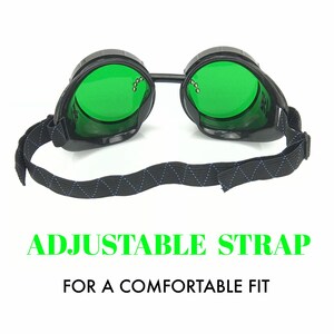 May include: Black safety goggles with green lenses and an adjustable strap. The strap is black with a blue and white diamond pattern. "ADJUSTABLE STRAP FOR A COMFORTABLE FIT" is written in green text below the goggles.