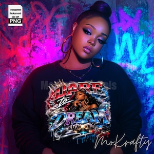 May include: Black sweatshirt with the text "DARE to DREAM" in a stylized design featuring a woman's portrait. The background is a graffiti-style wall with pink and blue hues. The sweatshirt has a crew neck and long sleeves.