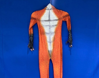May include: Orange and white fox costume with black accents. The full-body jumpsuit features a white chest and belly, with orange fur-like details. The sleeves and legs have black claw-like details at the ends. The costume is hanging against a blue background.