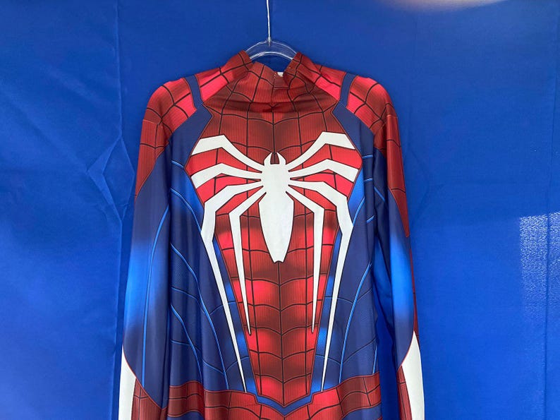 May include: A blue and red spandex costume with a white spider design on the chest. The costume has a high neck and long sleeves.