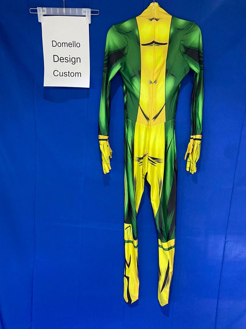 Op de afbeelding: Een groen en geel vol-body pak met een zwart ontwerp. Het pak hangt aan een hanger tegen een blauwe achtergrond. De tekst "Domello Design Custom" is zichtbaar op een wit label.